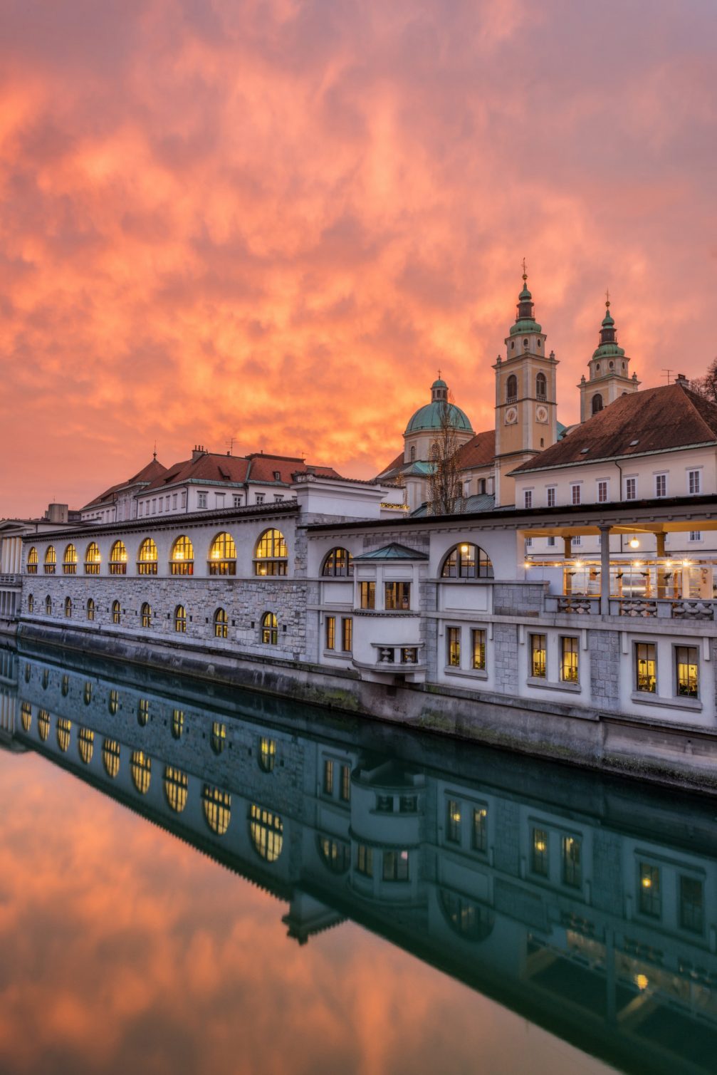 Central Market in Ljubljana with Ljubljana Cathedral in the background at sunset