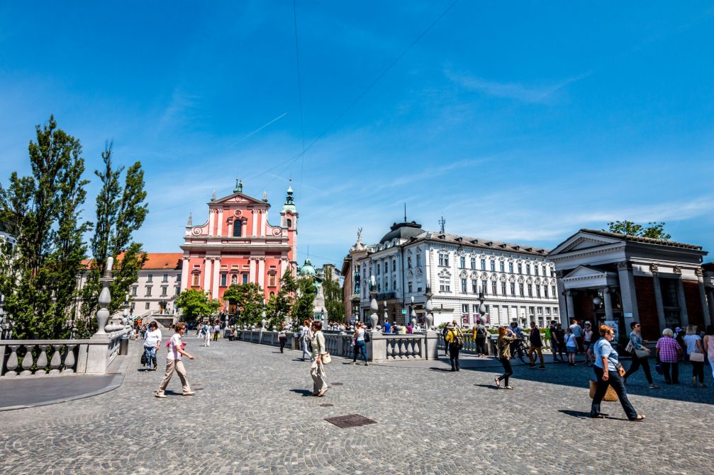 People walking over Triple Bridge in Ljubljana Old Town