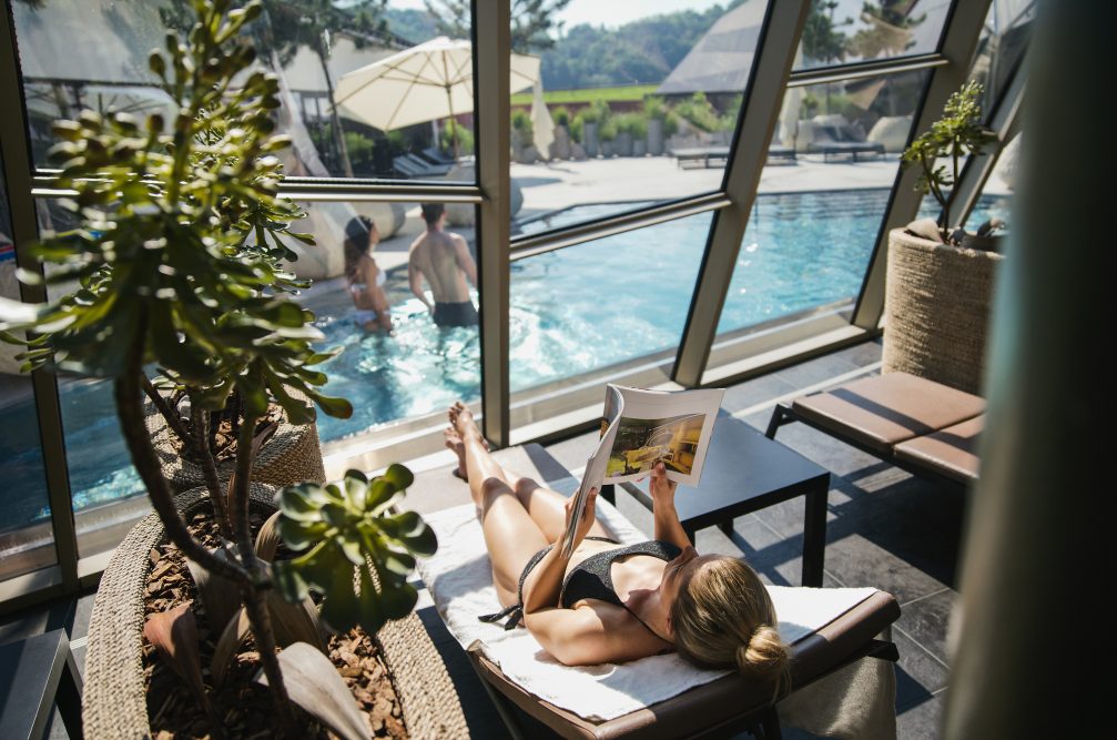 A woman reading a magazine on a sunbather at Wellness Orhidelia thermal spa in Terme Olimia in Podcetrtek