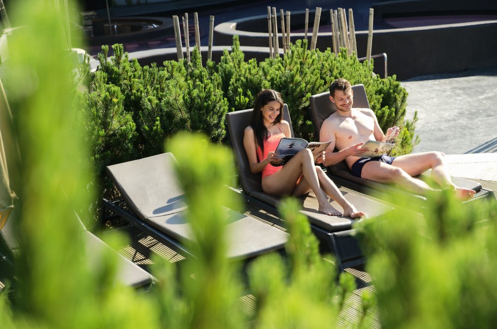 A couple reading a magazine on sunbathers at Wellness Orhidelia thermal spa in Terme Olimia